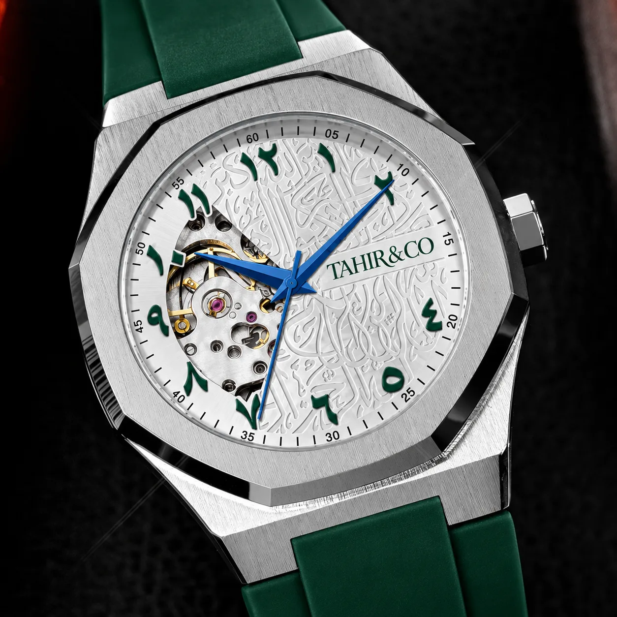 Angled view of the TAHIR & CO watch with green strap, silver calligraphy dial and blue hands