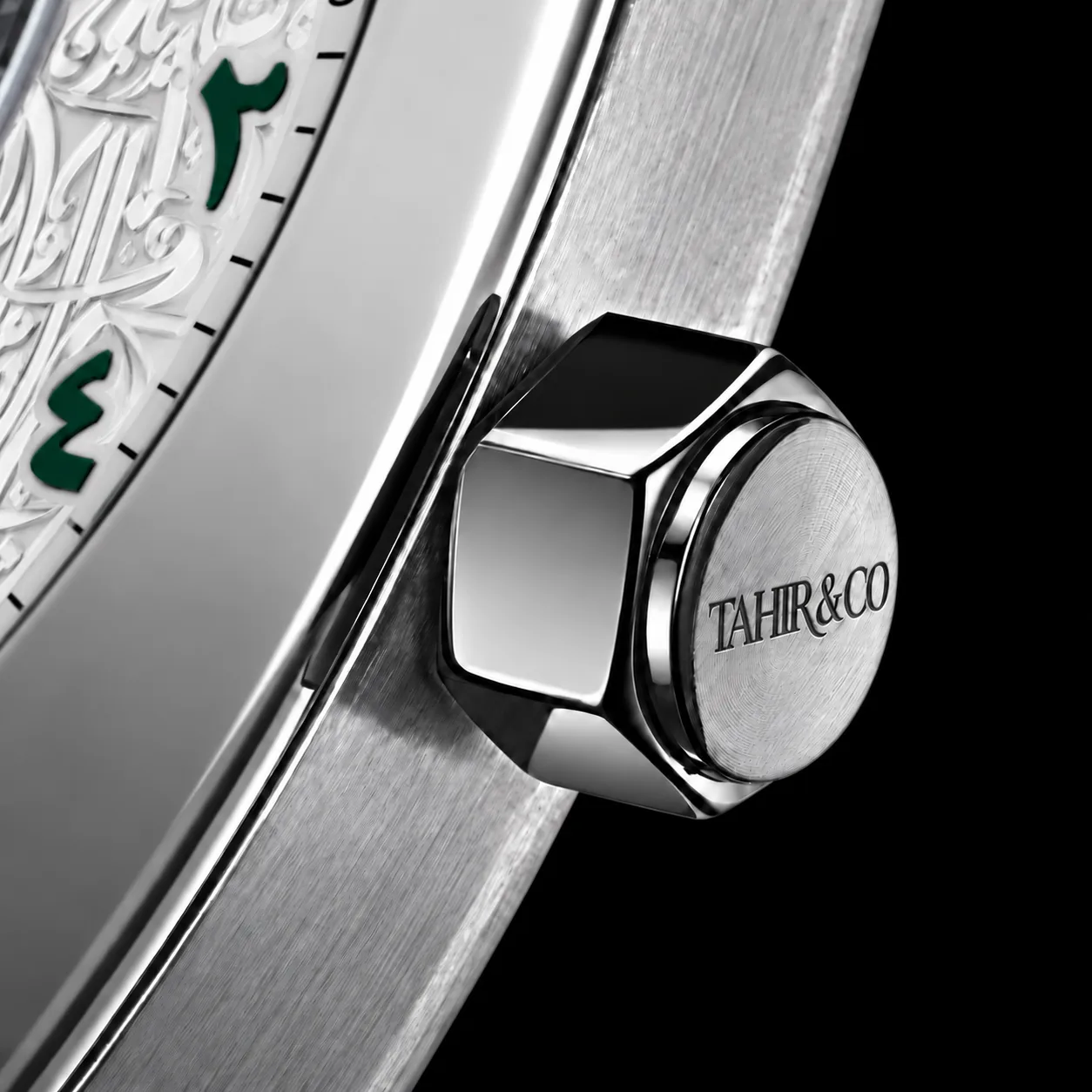Close-up of the hexagonal polished crown engraved TAHIR & CO beside the calligraphy dial